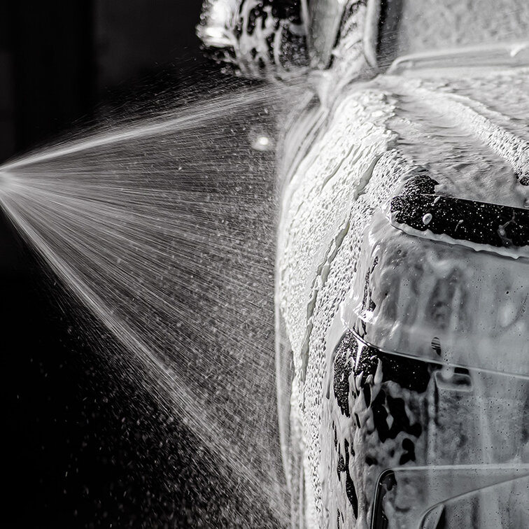 Close-up of foaming car wash shampoo on shiny car paint